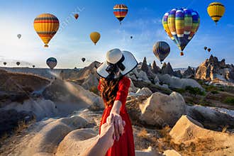 Women tourists holding man`s hand and leading him to hot air balloons in Cappadocia, Turkey.