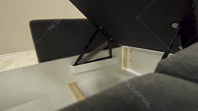 A chest of drawers of an angular black stylish sofa smoothly opens