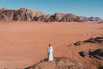 A man with local Arab dress standing on rock and looking to Wadi Rum desert in Jordan, Arab