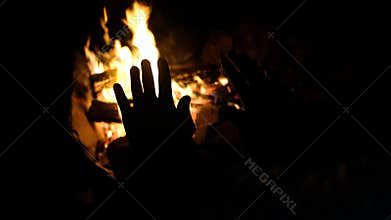 Hands of man warming up by camp fire. Body parts of adult male at nature.