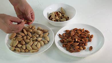 Female hands peel nuts from shells in a white plate