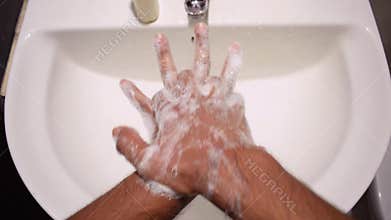 Man washing hands in sink with sanitiser liquid hand wash to prevent coronavirus