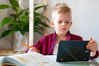 Distance learning online education. Schoolboy studying at home with digital tablet and doing school homework. Training