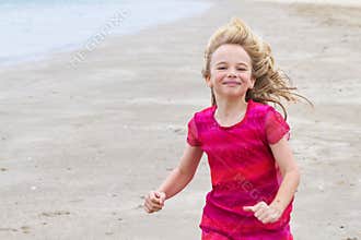 Little girl in red dress running on the beach