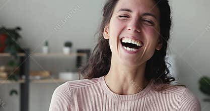 Cheerful young woman laughing looking at camera standing at home