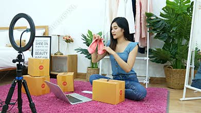 4K. Asian woman live streaming for selling shoe, fashion accessories online on social media via mobile phone from bedroom at home.