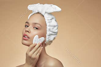 Beautiful girl with beauty gua Sha quartz stone for massage. The beige background is isolated. Cosmetic natural trend.