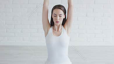 Beautiful woman stretching arms while doing yoga