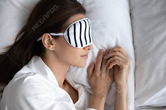 Tranquil young brunette woman wearing sleeping mask, sleeping at home.