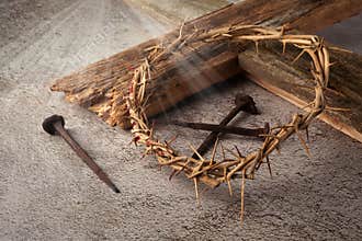 Easter background depicting the crucifixion with a rustic wooden cross, crown of thorns and nails.