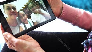 Senior woman alone at home video chatting with her family