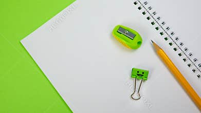 School Notepad with Yellow Pencil, Smile Binder Clip and Pencil Sharpener on Green Background
