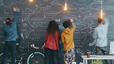 Time lapse of creative youth coworkers writing and drawing on black chalkboard indoors