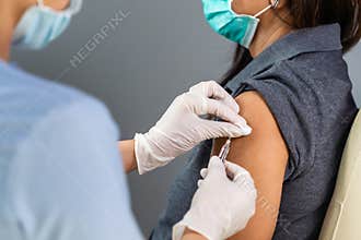 Doctor holding syringe and using cotton before make injection to patient in medical mask. Covid-19 or coronavirus vaccine