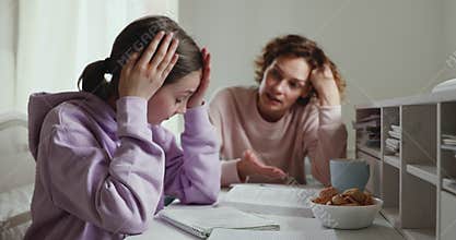 Angry mom scolding stressed daughter for bad school results.