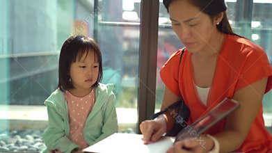 4K slow motion of asian parent and obedient child reading at the library