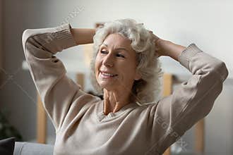 Happy 60s mature woman feel optimistic relaxing at home