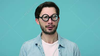 Closeup of comical awkward geek adjusting round diopter eyeglasses looking around with silly funny grimace