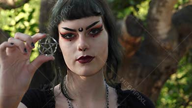 A Wiccan teen girl holds up a pentagram, symbol of her belief.