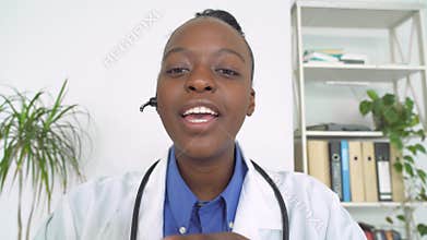 African female doctor wear headset make video call, webcam view.