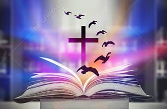 The Christian Cross is illuminated in a book in white and fantasy light, with magic shining as hope, love and freedom in beautiful