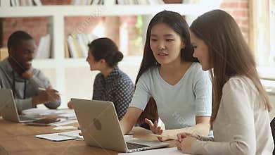 Friendly diverse girls students talking in classroom using laptop