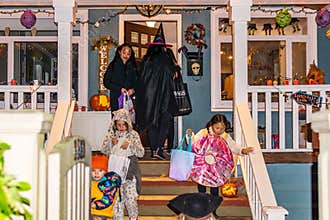 VANCOUVER, CANADA - October 31, 2019: Children in costumes knocking on door of decorated house trick or treat halloween
