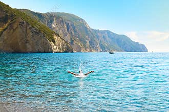 A tourist plays and splashes in the sea at Chomi or Paradise Beach on the Greek Island of Corfu