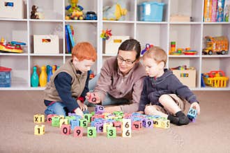Boys playing game with kids blocks with mother