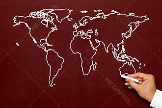 World map on blackboard. A hand draws a stylized globe map of the world with all continents with white chalk on a red chalkboard