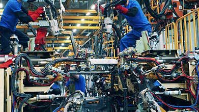 Car body workers welding car body at a car manufacturing facility.