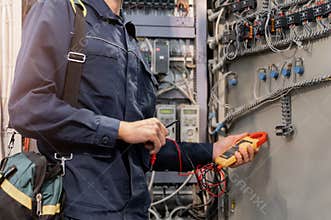 Electrician engineer checks electrical circuit in control panel for high current and voltage, starting and commissioning