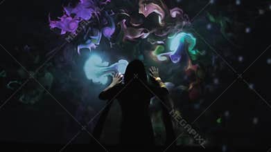 Girl plays with interactive video installation, hands draw the shape heart. New art form, generative graphics