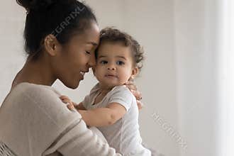 Bonding mixed race young mommy cuddling sweet little kid.