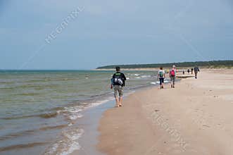Group of hikers on the sandy coastline of Baltic sea