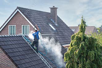Cleaner with pressure washer at roof house cleaning roof tiles
