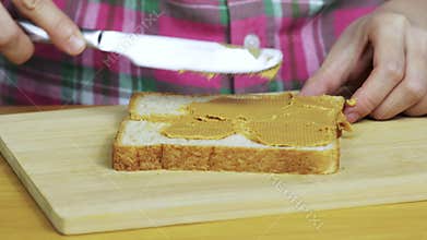Woman making a peanut butter and Strawberry Jam sandwich