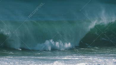 Large waves with white foam roll on beach of azure ocean