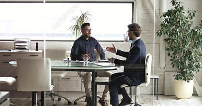 Motivated young businessmen shaking hands after making agreement.