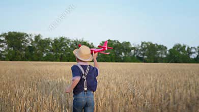 Joyful childhood, male child likes to play in wheat field, running with toy airplane in hands