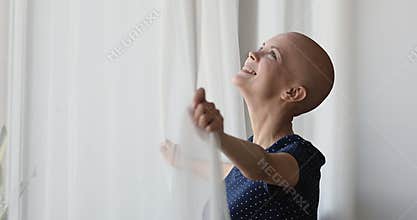 Cancer patient standing near window looks outside breath fresh air
