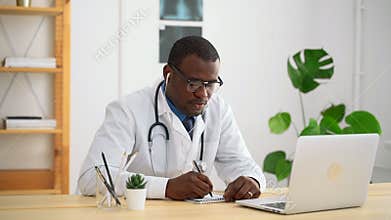 Young male doctor is writing during online consultation at table in modern clinic spbas.