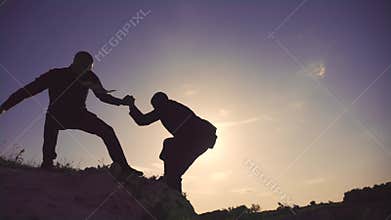 Teamwork. help business travel silhouette concept. group team of tourists lends helping hand a climb the cliffs