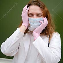 Tired school nurse in a medical mask on a blackboard background. Learning difficulties in the flu pandemic