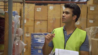 20s Indian distribution shipping depot worker walking and check inventory. Male worker in working uniform at storehouse