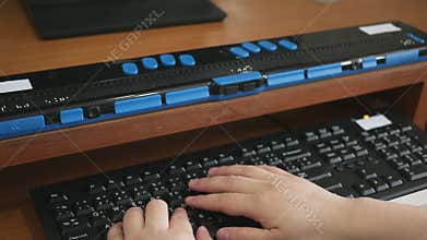 Close-up blind person woman hands using computer keyboard and braille display or braille terminal a technology assistive device