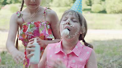 The girl has whipped cream on her face, a dirty face. Birthday celebrations.