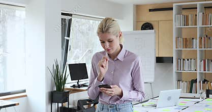 Businesswoman holding cellphone emailing to client consider answer, looks thoughtful