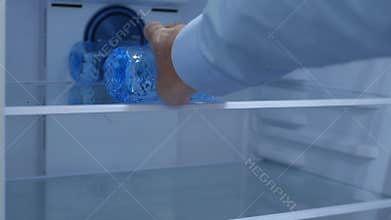 Man Opens the Fridge Door and Put a Bottle with Water to Chill