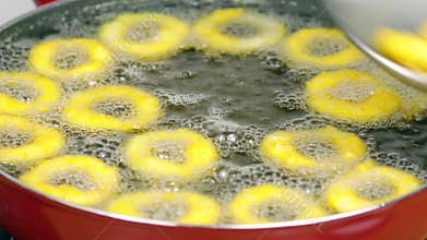 Deep frying onion rings in a red skillet